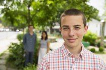 Portrait of boy on street with adults standing in background. — Stock Photo