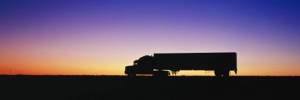 Silhueta de semi-caminhão contra o céu dramático — Fotografia de Stock