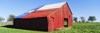 Красный амбар в поле с флагом Техаса на крыше в США — стоковое фото