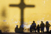 Ombres de croix et silhouettes de personnes contre le mur jaune — Photo de stock