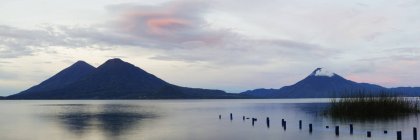 Sílhuetas de vulcões sobre a água no lago Atitlan, Guatemala — Fotografia de Stock