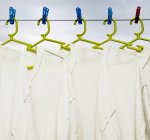 Shirts hanging to dry on green hangers — Stock Photo