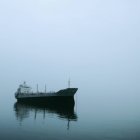 Nave da carico su acqua nebbia con riflessione sulla superficie dell'acqua — Foto stock