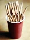 Primo piano di matite di legno in tazza di plastica rossa sul tavolo — Foto stock