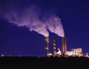 Des cheminées de fumée gonflent la fumée la nuit dans une usine industrielle à Apollo Beach, Floride, États-Unis — Photo de stock