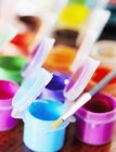 Close-up of multi-colored poster paints and paintbrush — Stock Photo