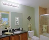 Salle de bain bien meublée avec de nouvelles serviettes et miroir — Photo de stock
