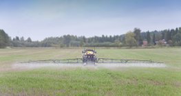 Tractor rociando herbicidas en el campo, Estonia - foto de stock