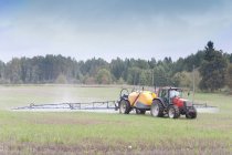 Tractor spraying herbicides in countryside field, Estonia — Stock Photo