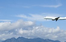 Un avion commercial arrive pour atterrir dans un ciel nuageux bleu à Vancouver, Canada — Photo de stock