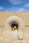 Традиционная печь с горящими бревнами, Пуэбло-де-Таос, Нью-Мексико, США — стоковое фото