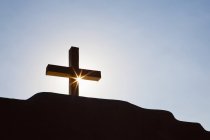 Крест и солнце на фоне голубого неба в спину зажглись — стоковое фото