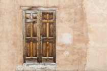 Old wooden door in weathered adobe house facade, Santa Fe, New Mexico, USA — Stock Photo