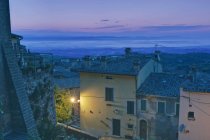 Montecchiello Dorf beleuchtete Straße mit Gebäuden in der Morgendämmerung, Toskana, Italien — Stockfoto
