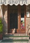 Entrada al restaurante La Grotta con gato sentado en Montepulciano, Toscana, Italia - foto de stock