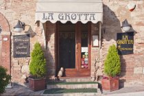 La Grotta Restaurant Eingang mit sitzender Katze in Montepulciano, Toskana, Italien — Stockfoto