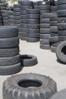 Piles de pneus automobiles usagés empilées à l'extérieur — Photo de stock