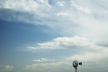 Ветряная мельница против голубого неба с белыми облаками — стоковое фото