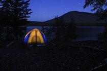 Acampamento com tenda iluminada à noite, Bowron Lake Provincial Park, Canadá — Fotografia de Stock