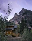 Maison de montagne dans les bois au crépuscule sous le ciel crépusculaire — Photo de stock