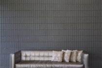 Sofá moderno con almohadas contra pared de ladrillo - foto de stock