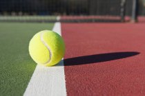 Close-up of tennis ball on tennis court in sunlight — Stock Photo