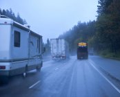 Freeway traffic in rain in countryside woodland road — Stock Photo