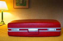 Primer plano de la maleta roja en la habitación del motel - foto de stock