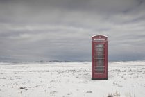 Teléfono tradicional del Reino Unido en una ubicación remota en un paisaje invernal cubierto de nieve - foto de stock