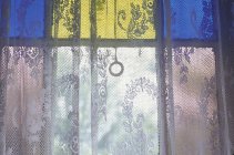 Close-up of lace curtain and stained glass window pane — Stock Photo