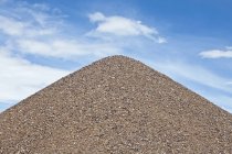 Gravel pile against blue sky with white clouds — Stock Photo