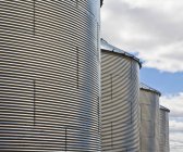 Linha de silos de grãos de metal contra o céu azul nublado, Wyoming, EUA — Fotografia de Stock