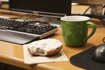 Close-up of coffee cup and bagel on work desk — Stock Photo