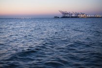 Loading cranes and lights blurred over water surface at dusk, Norfolk, Virginia, USA — Stock Photo