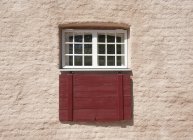 Fachada de edificio tradicional con ventana protegida con rejilla y persianas de madera - foto de stock