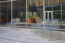 Ряд сучасних світлопрозорих стільців на дерев'яній підлогове покриття великими вікнами — стокове фото