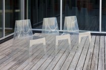 Ряд сучасних напівпрозорих стільців на дерев'яній підлозі — стокове фото
