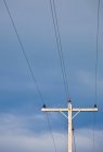 Pôle téléphonique avec fils contre ciel bleu — Photo de stock