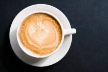 Tasse Kaffee auf schwarzem Hintergrund, Draufsicht — Stockfoto