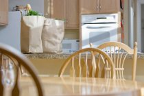 Küche mit Lebensmitteln, Holztisch und Stühlen — Stockfoto