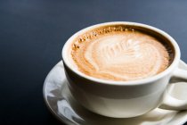 Blatt-Design in Espresso-Schaum, Nahaufnahme der weißen Tasse auf schwarzem Hintergrund — Stockfoto