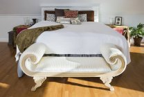 Скамейка у кровати в современном интерьере квартиры — стоковое фото