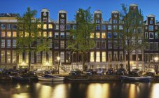 Autos y casas frente al canal por la noche en Amsterdam, Países Bajos - foto de stock
