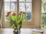 Tulipani in vaso sul tavolo dalla finestra della casa — Foto stock