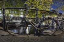 Bicicletas aseguradas a la barandilla del canal en Amsterdam, Países Bajos - foto de stock