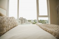 Dormitorio monocromático en beige con ciudad detrás de ventana - foto de stock