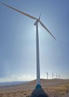 Ветровые турбины на полях холмов против голубого неба с белыми облаками — стоковое фото