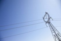 Strommast mit Stromleitungen gegen blauen Himmel — Stockfoto