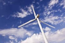 Ветровая турбина под облаками в голубом небе — стоковое фото