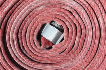 Coiled red fire hose, close-up — Stock Photo